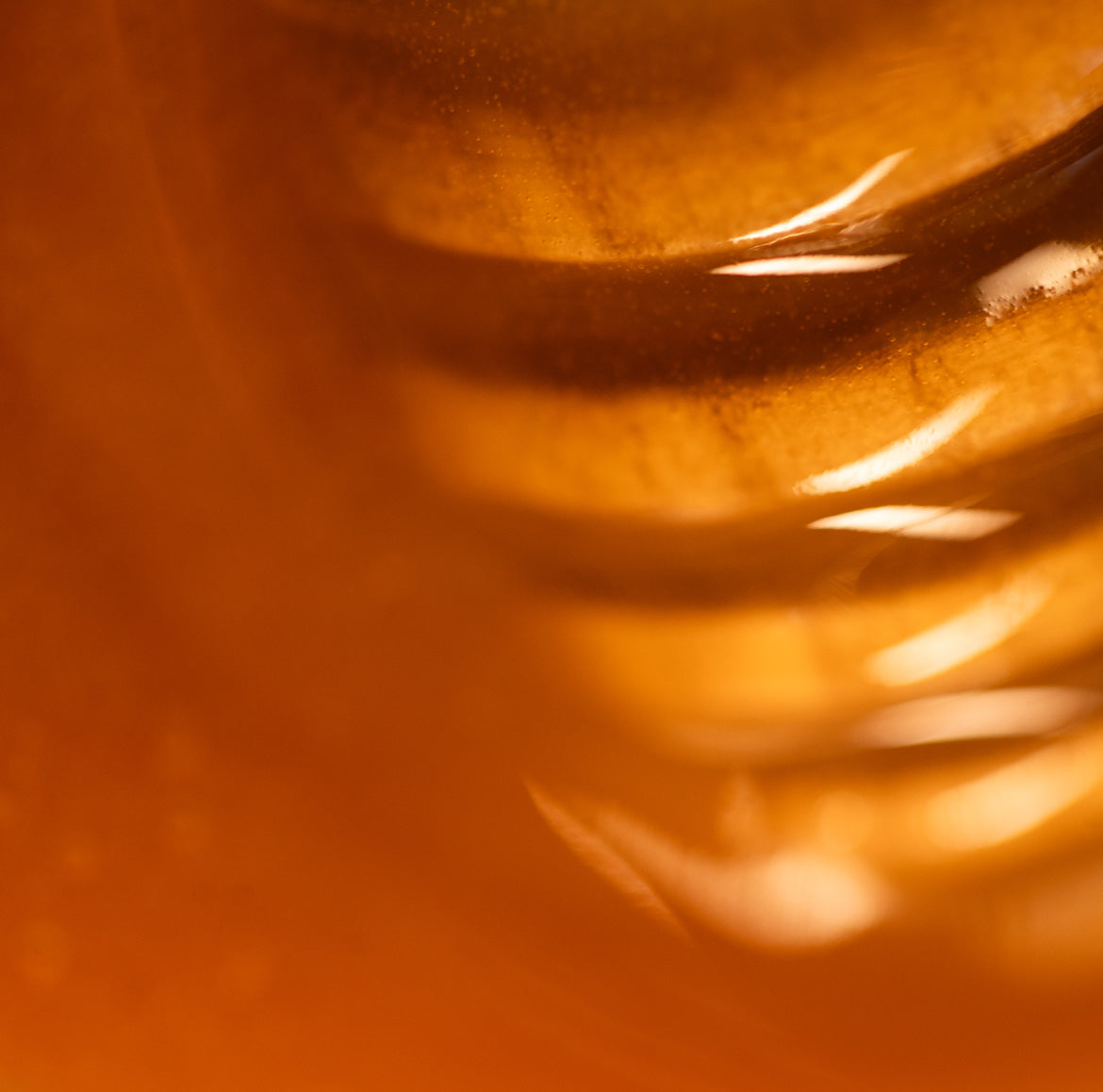 Rich Naki mānuka honey on a wooden spoon, showing its thick golden texture and depth of colour